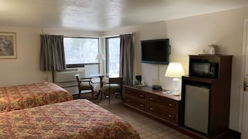 Habitación de hotel con dos camas, un escritorio, un televisor, un microondas y un aparador.