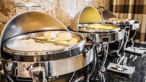 Buffet-style food service with multiple stainless steel chafing dishes.