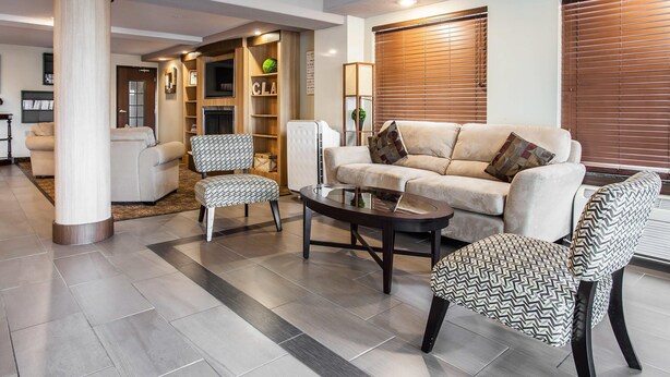 A modern living room with a sofa, two patterned chairs, a coffee table, and a fireplace.