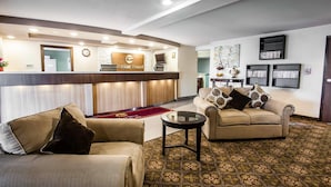 A hotel reception area with a reception desk, a sofa, a coffee table, and a patterned carpet.