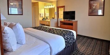 Una habitación de hotel con cama, cómoda, televisor y espejo.
