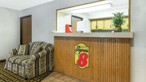 Un área de recepción con un mostrador de madera, un sofá floral y una planta en maceta.