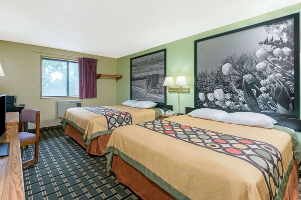 A hotel room with two beds, a desk, a chair, a window with curtains, a lamp, and two wall-mounted lamps.