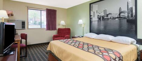 A hotel room with a bed, a desk with a television, a chair, a window with curtains, and a cityscape painting on the wall.