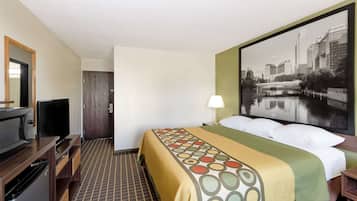 A hotel room with a bed, a TV, a desk, and a large window with a cityscape view.