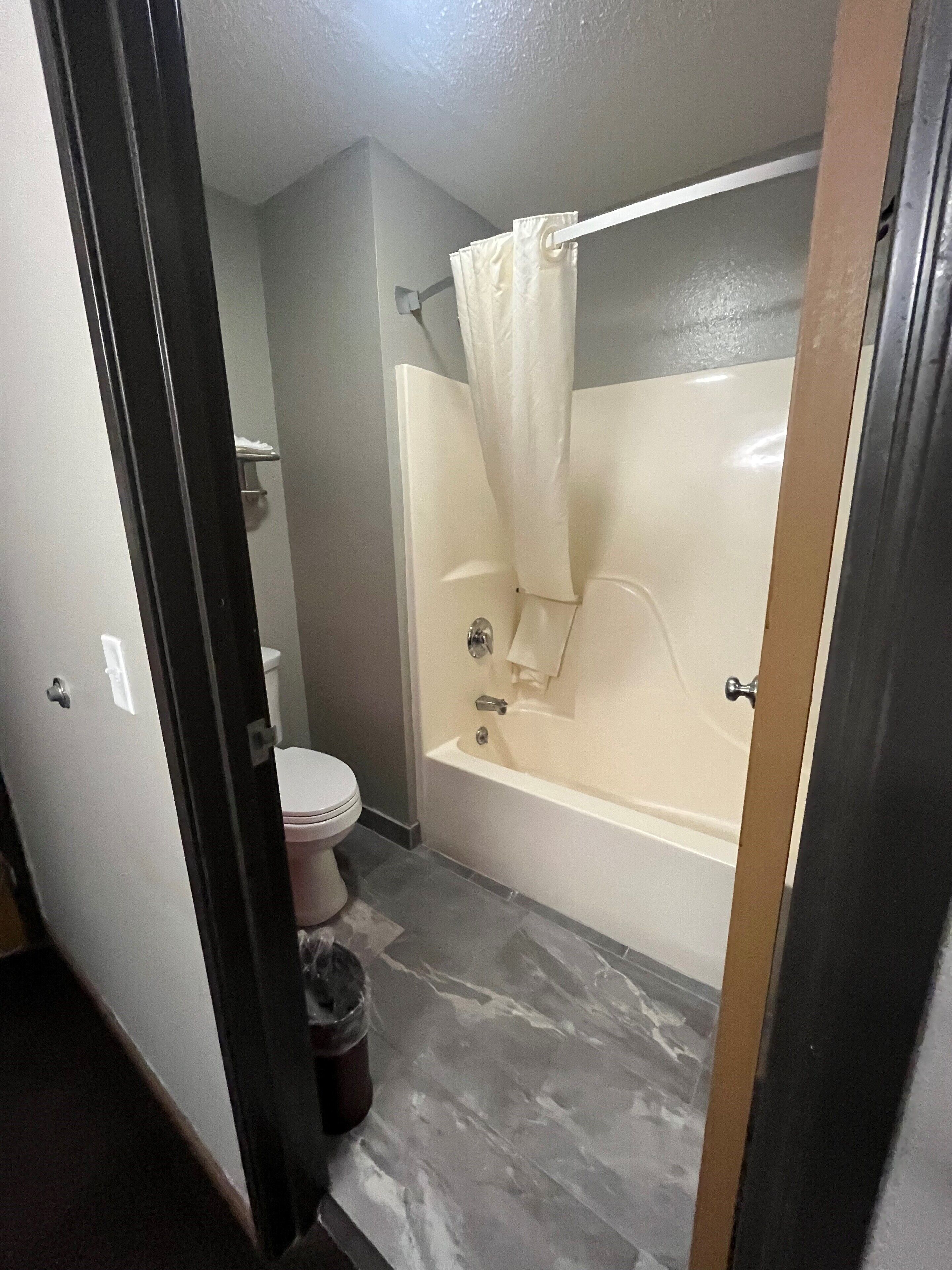 A bathroom with a toilet, a bathtub, and a shower curtain.