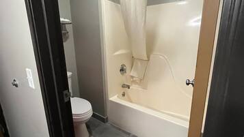 A bathroom with a toilet, a bathtub, and a shower curtain.