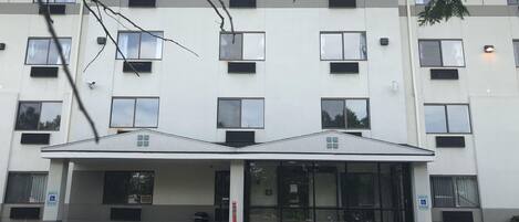 Um edifício de vários andares com telhado plano, janelas amplas e entrada coberta.