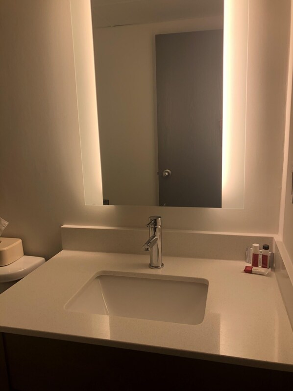 Un baño con un lavamanos blanco, un espejo y un inodoro.