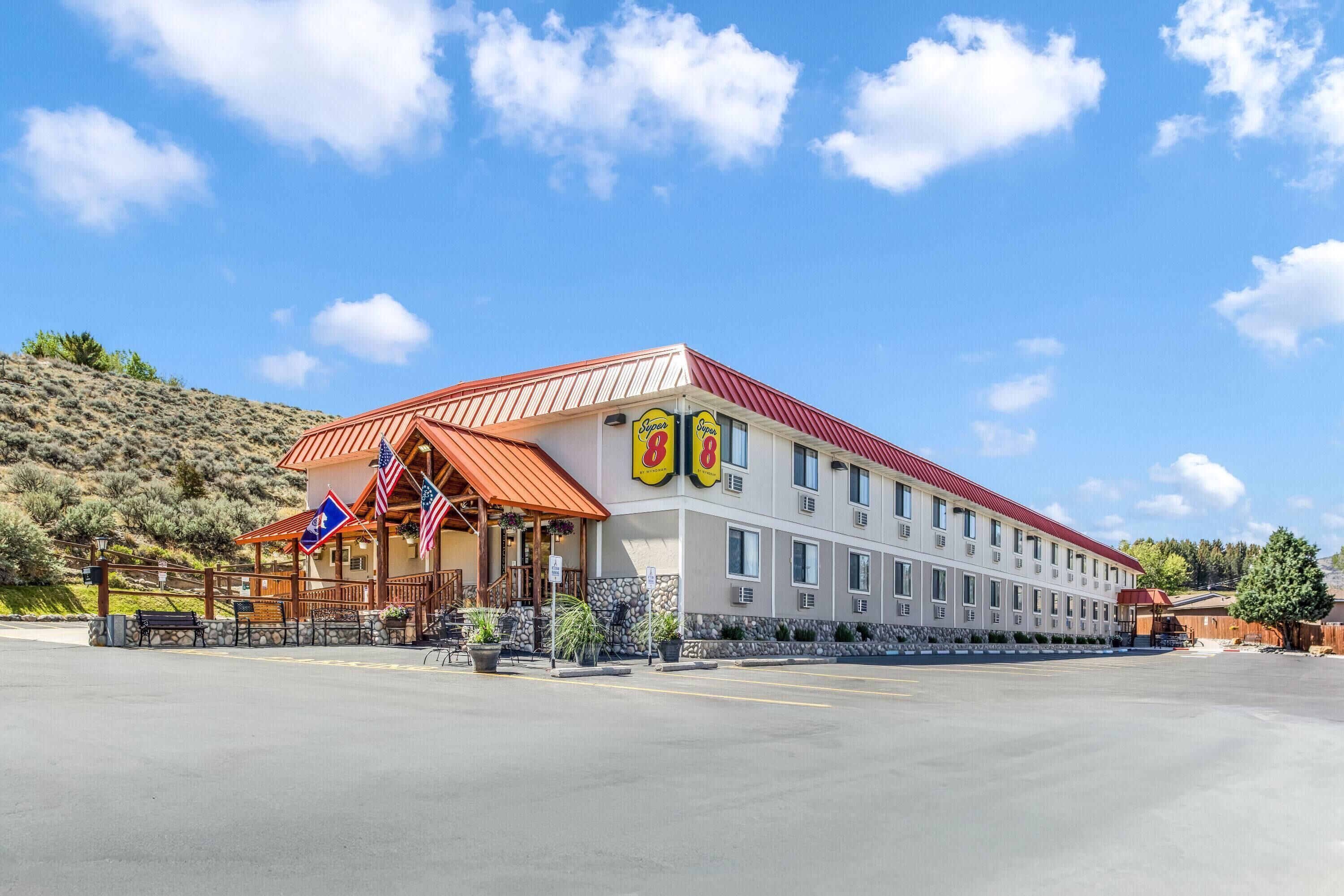 Un hotel con techo rojo, entrada cubierta y banderas.
