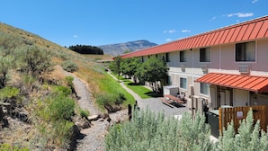 A hotel with a red roof, a gravel path, and a view of mountains. - Super 8 by Wyndham Cody (Cody)