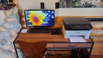 A wooden desk with a computer monitor, keyboard, mouse, and a Samsung printer.