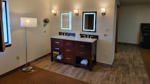A bathroom with a double sink vanity, two wall-mounted mirrors, and a floor lamp. - Super 8 by Wyndham Cody (Cody)