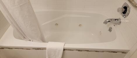 A bathroom with a bathtub, a shower curtain, a grab bar, and a towel.