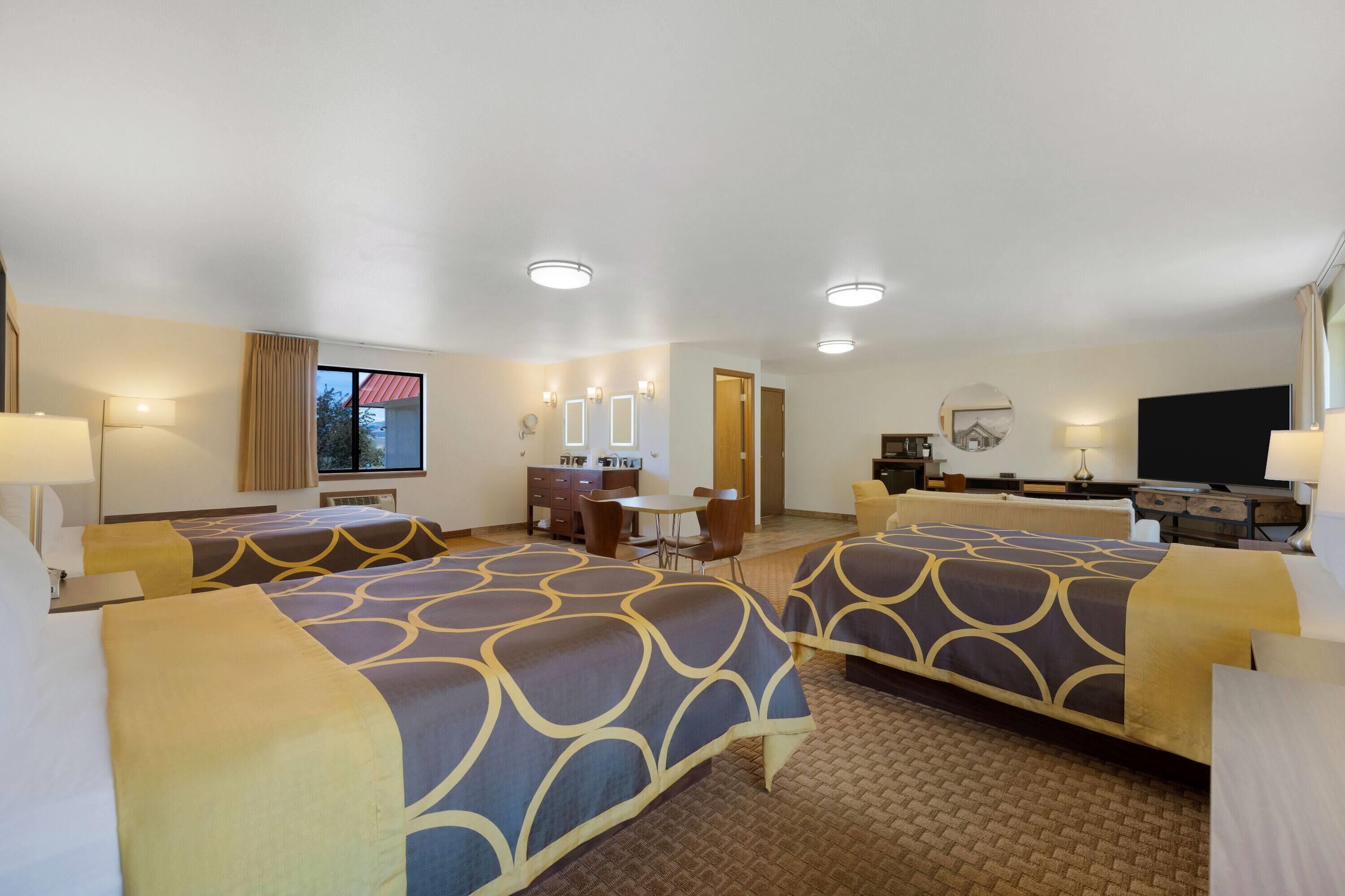 A hotel room with two beds, a desk, a chair, a television, and a window with curtains.