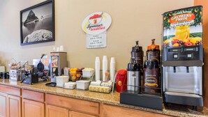 A breakfast bar with a coffee machine, juice dispenser, and various food items. - Super 8 by Wyndham Corvallis (Corvallis)