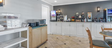 Una cocina moderna con estación de café, microondas y zona de estar con sillas.