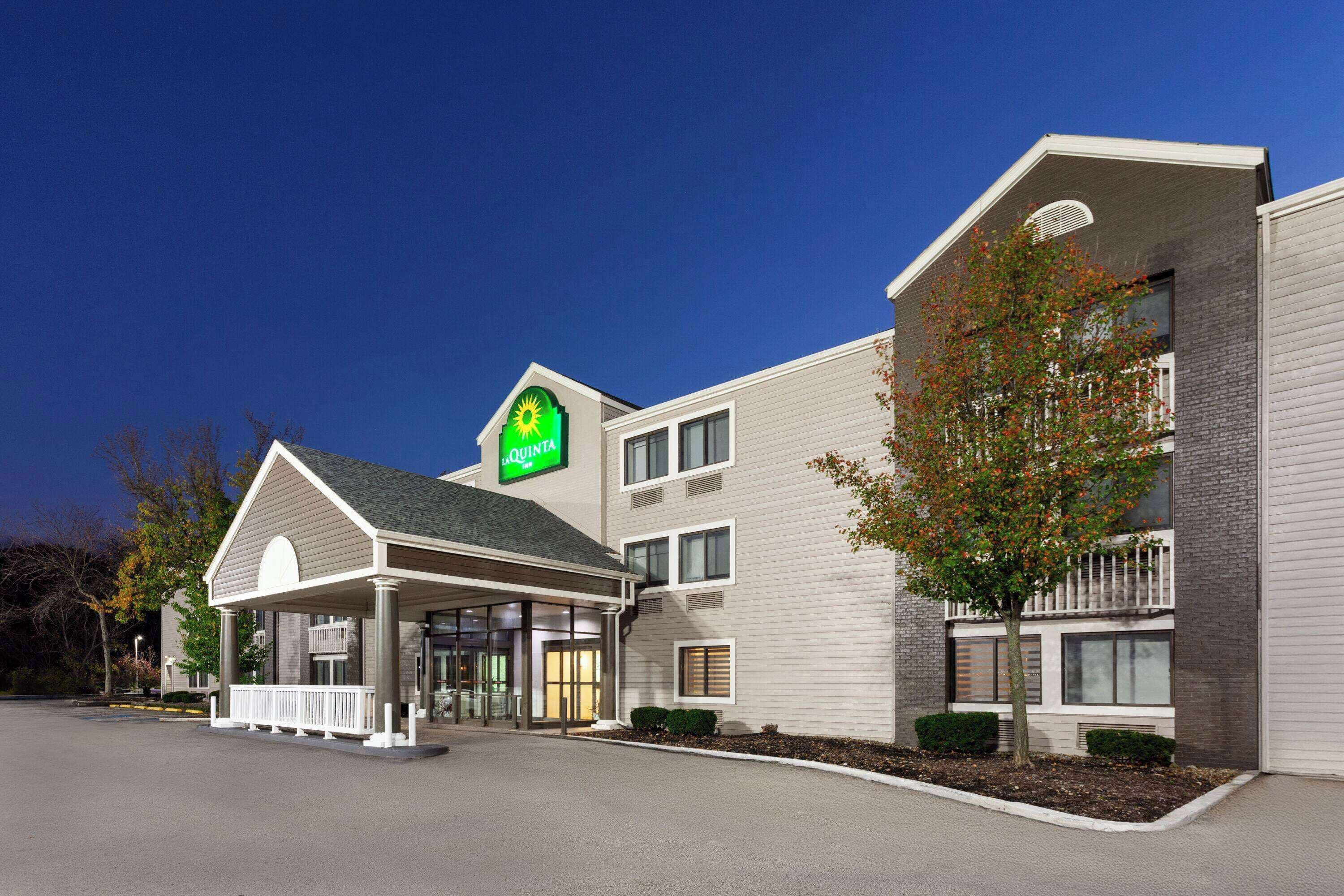 A hotel with a prominent 'Quinta' sign, a covered entrance, and a landscaped area with a tree.