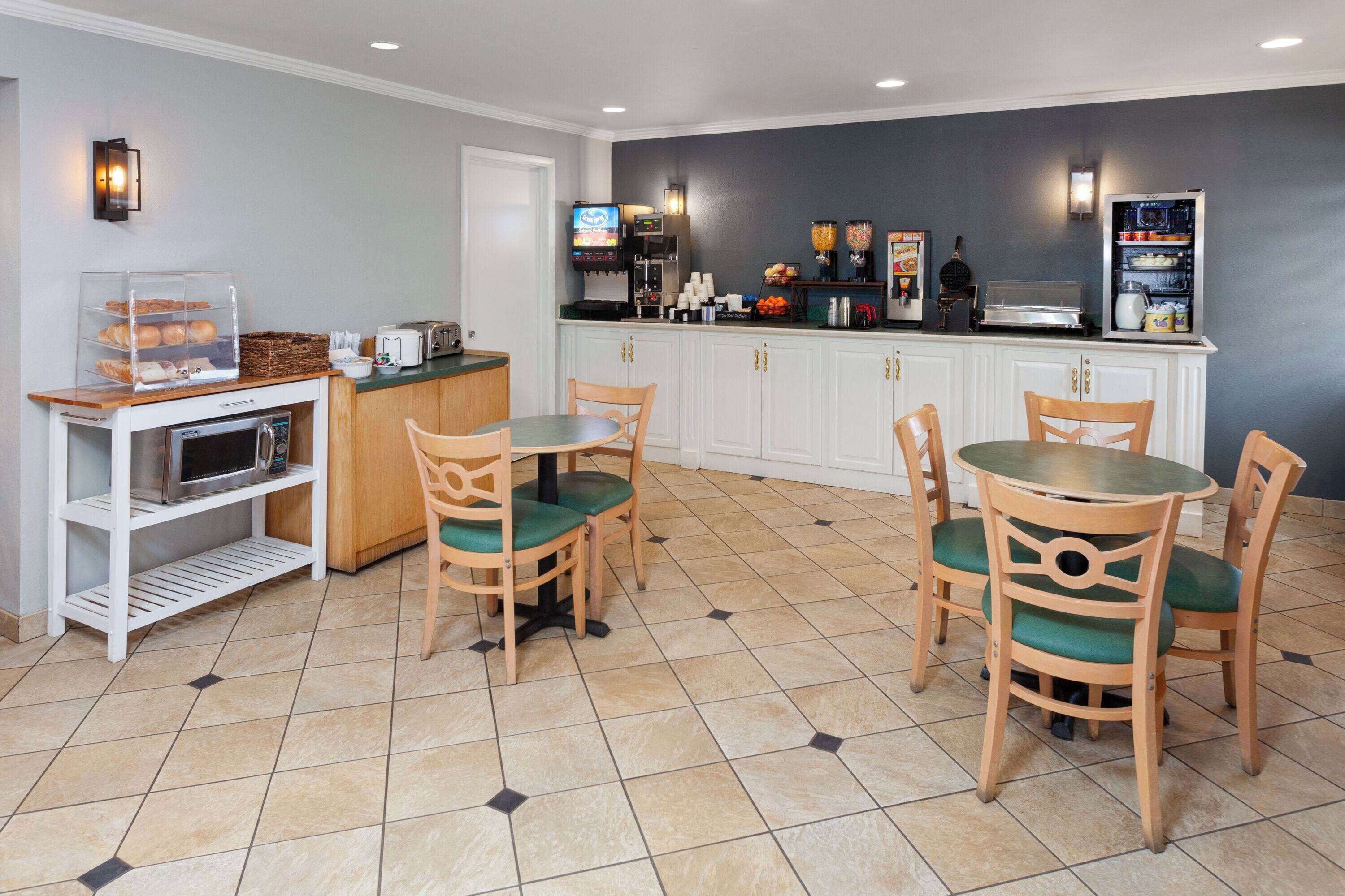 Una cocina de hotel con barra de desayuno, microondas y estación de café.