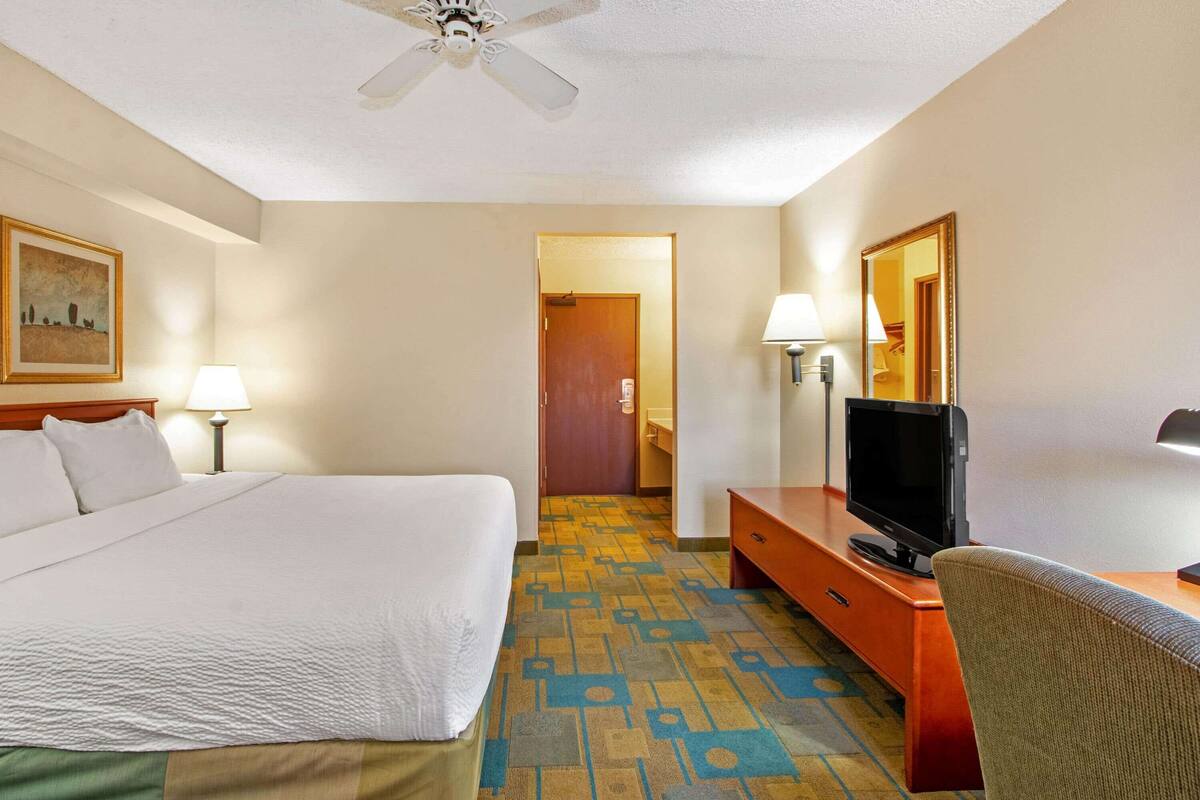 A hotel room with a bed, a television, a desk, and a chair.