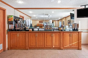 A hotel kitchen with a wooden counter, coffee machines, and a large mirror.