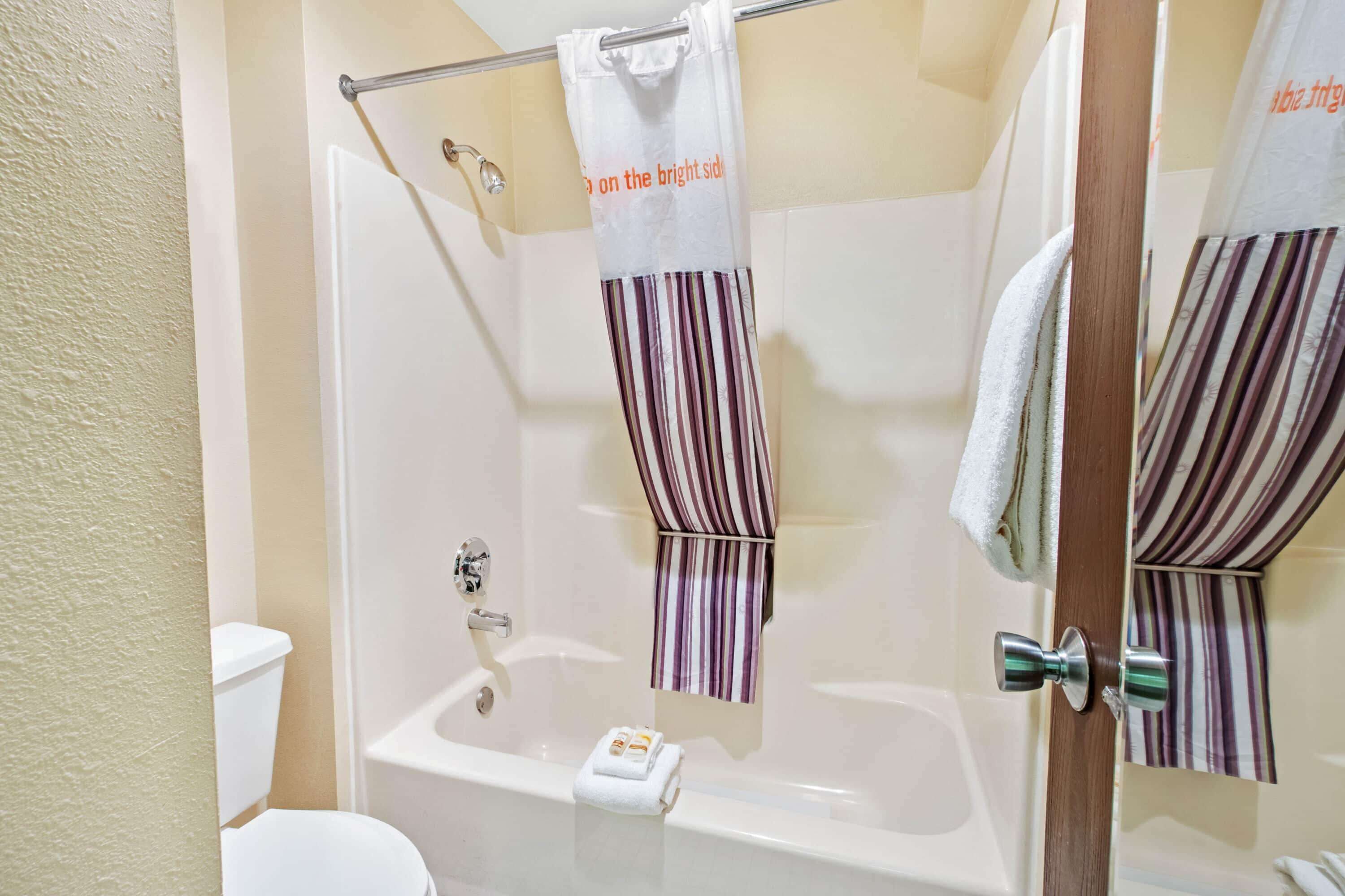 A bathroom with a bathtub, a toilet, and a shower curtain.