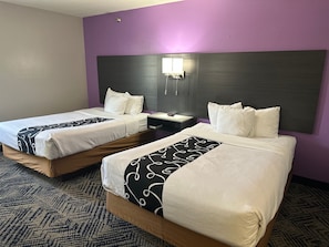 A hotel room with two beds, a nightstand, and a wall-mounted lamp. - La Quinta Inn by Wyndham Omaha Southwest (Omaha)