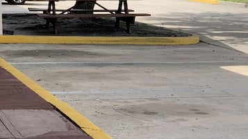 A picnic table in a parking lot with a tree nearby.