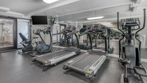 A gym with treadmills, elliptical machines, and a mirrored wall.