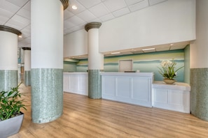 A lobby with a reception desk, columns, and a wooden floor.