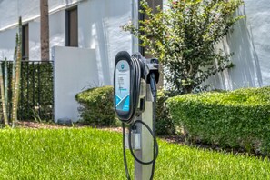 An electric vehicle charging station with a clear label, set against a backdrop of a building and greenery. - Best Western Orlando Gateway Hotel (Orlando)