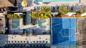 An aerial view of a rooftop pool area with two smaller pools, a basketball court, and lounge seating. - Best Western Orlando Gateway Hotel (Orlando)
