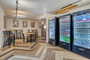A hotel room with a dining area, three beverage air coolers, and a ceiling fan.
