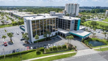 A modern building with a glass facade, parking lot, and a small water feature.