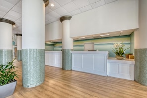 A lobby with a reception desk, columns, and a wooden floor.