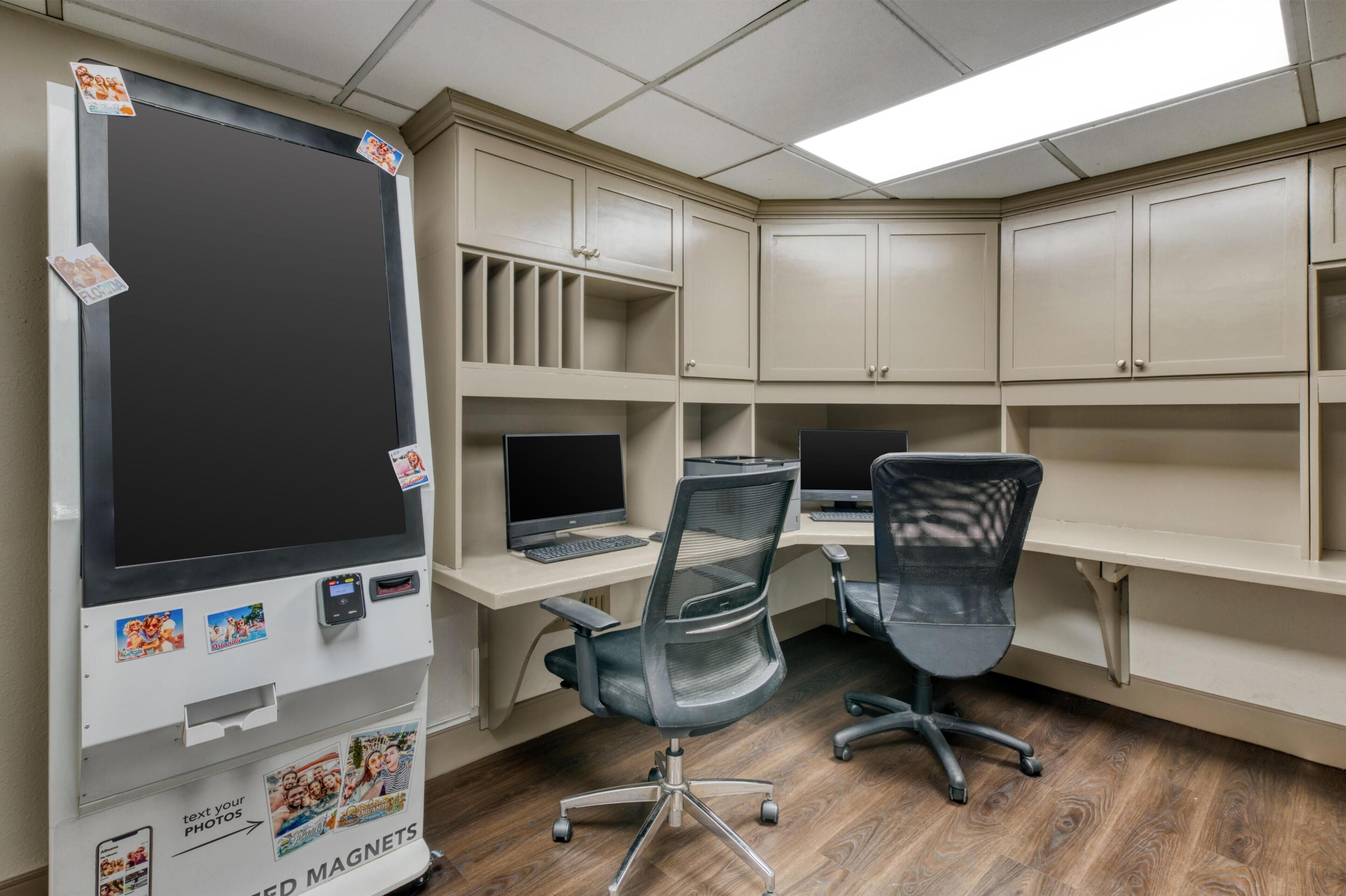 Een kamer met twee bureaus, twee stoelen en een groot machine om foto's af te drukken.