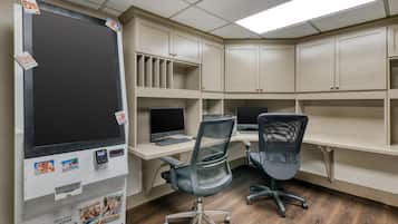 Een kamer met twee bureaus, twee stoelen en een groot machine om foto's af te drukken.