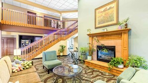 A spacious lobby with a wooden staircase, a fireplace, and comfortable seating areas. - Best Western Holiday Manor (Newton)