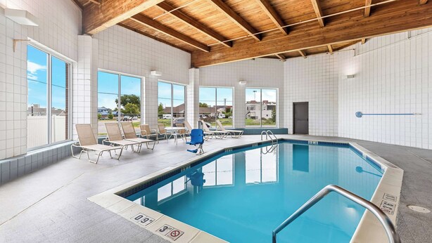 An indoor swimming pool with tiled walls, wooden ceiling beams, and lounge chairs. - Best Western Holiday Manor (Newton)