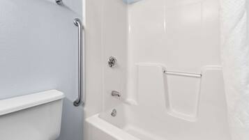 Une salle de bain avec une baignoire blanche, des toilettes et un espace douche.