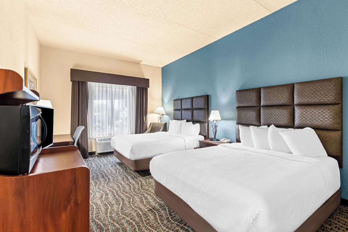 A hotel room with two beds, a desk, and a television.