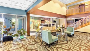A spacious lobby with a patterned carpet, seating areas, and a staircase. - Best Western Holiday Manor (Newton)
