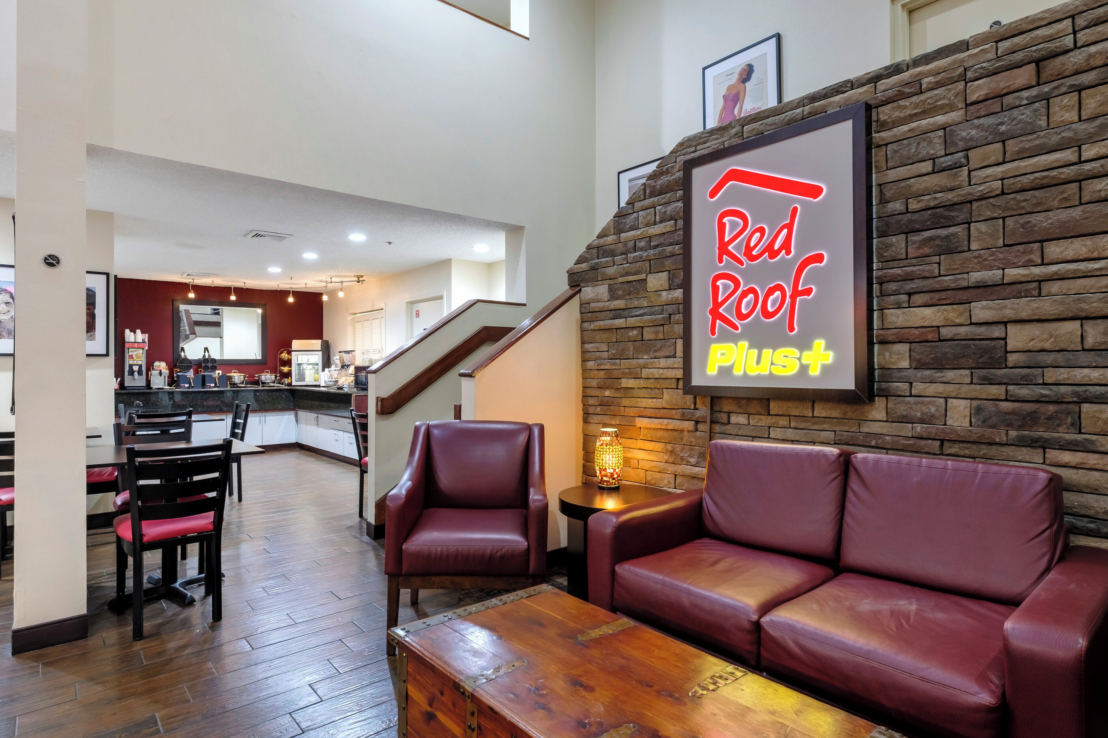 Un área de descanso Red Roof Plus con asientos de cuero y una mesa de centro de madera.