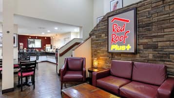 Un área de descanso Red Roof Plus con asientos de cuero y una mesa de centro de madera.