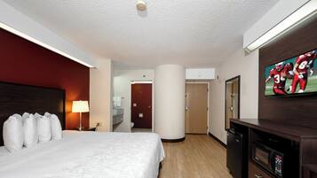 Une chambre d’hôtel avec un lit, une télévision, un bureau et une salle de bain visible à travers une porte ouverte.
