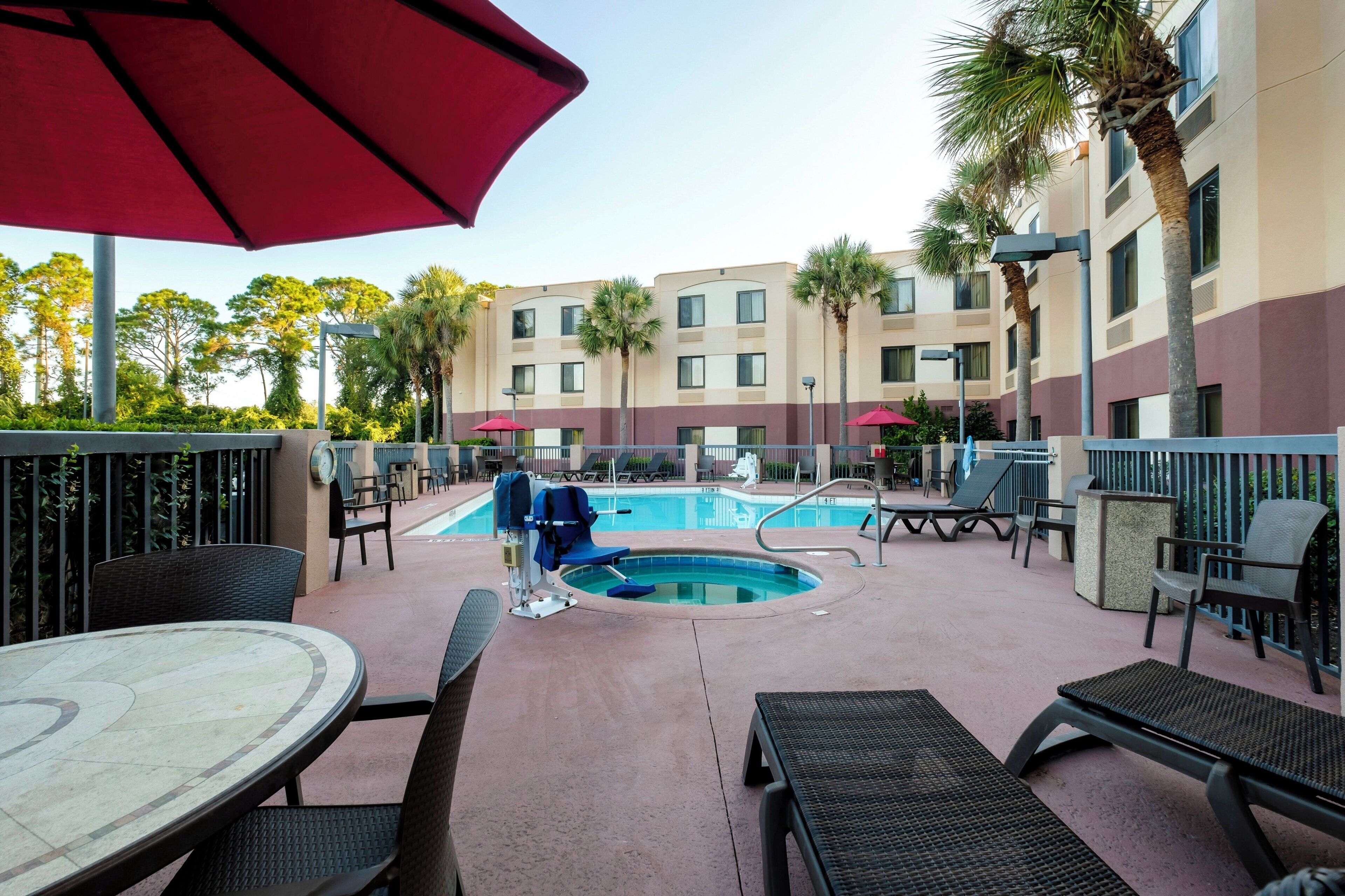 A pool area with lounge chairs, a table, and umbrellas.