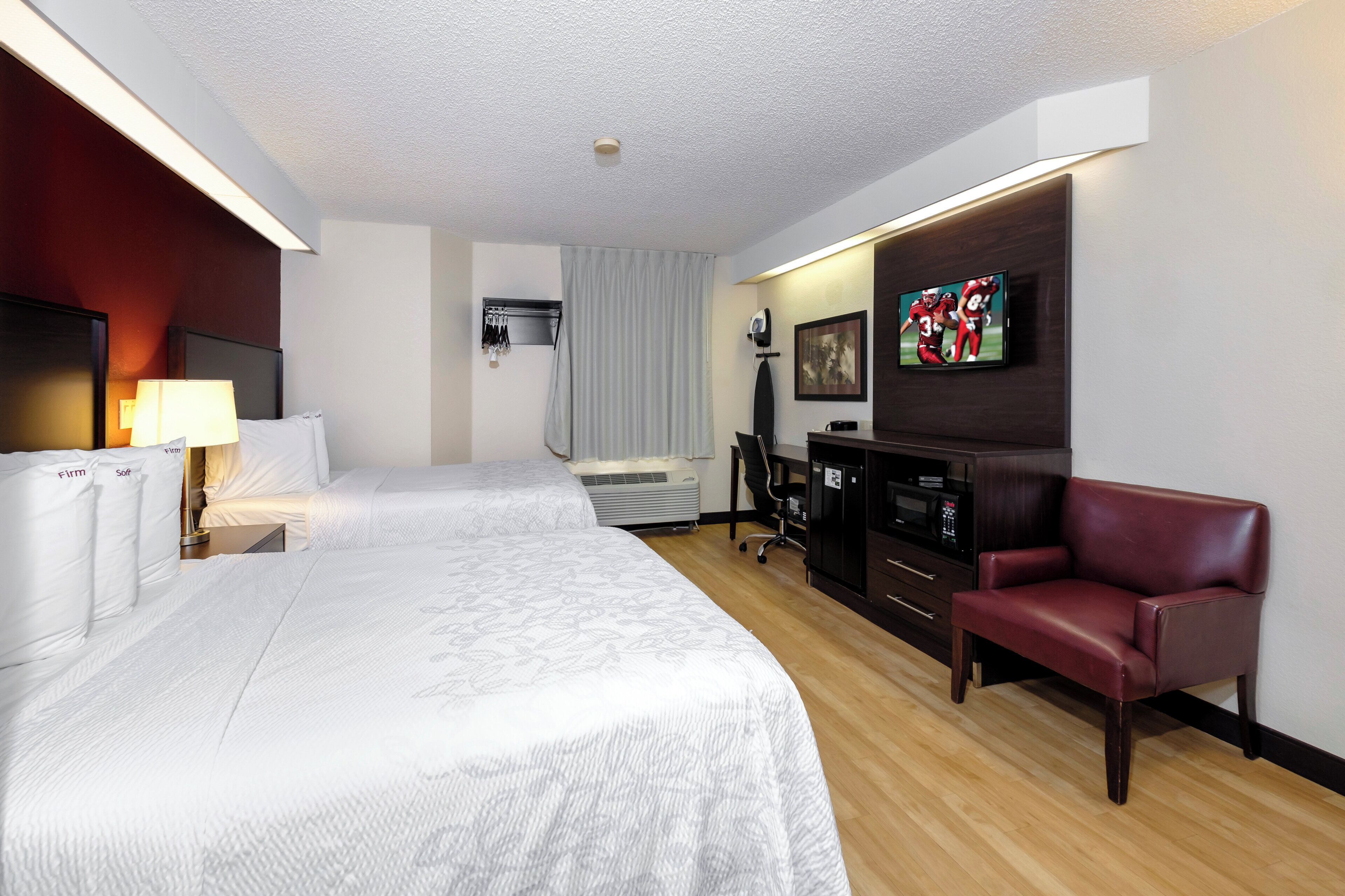 Ein Hotelzimmer mit einem großen Bett, einem Schreibtisch, einem Fernseher und einem Ledersessel.