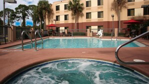 A hotel pool area with a hot tub, lounge chairs, and palm trees. - Red Roof Inn PLUS+ Palm Coast (Palm Coast)