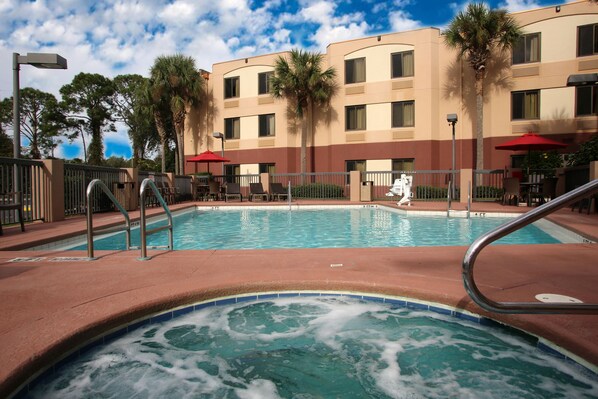 A hotel pool area with a hot tub, lounge chairs, and palm trees. - Red Roof Inn PLUS+ Palm Coast (Palm Coast)