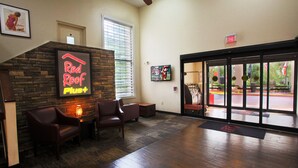 A lobby with a Red Roof Pizza sign, leather chairs, a fireplace, and a door leading outside. - Red Roof Inn PLUS+ Palm Coast (Palm Coast)